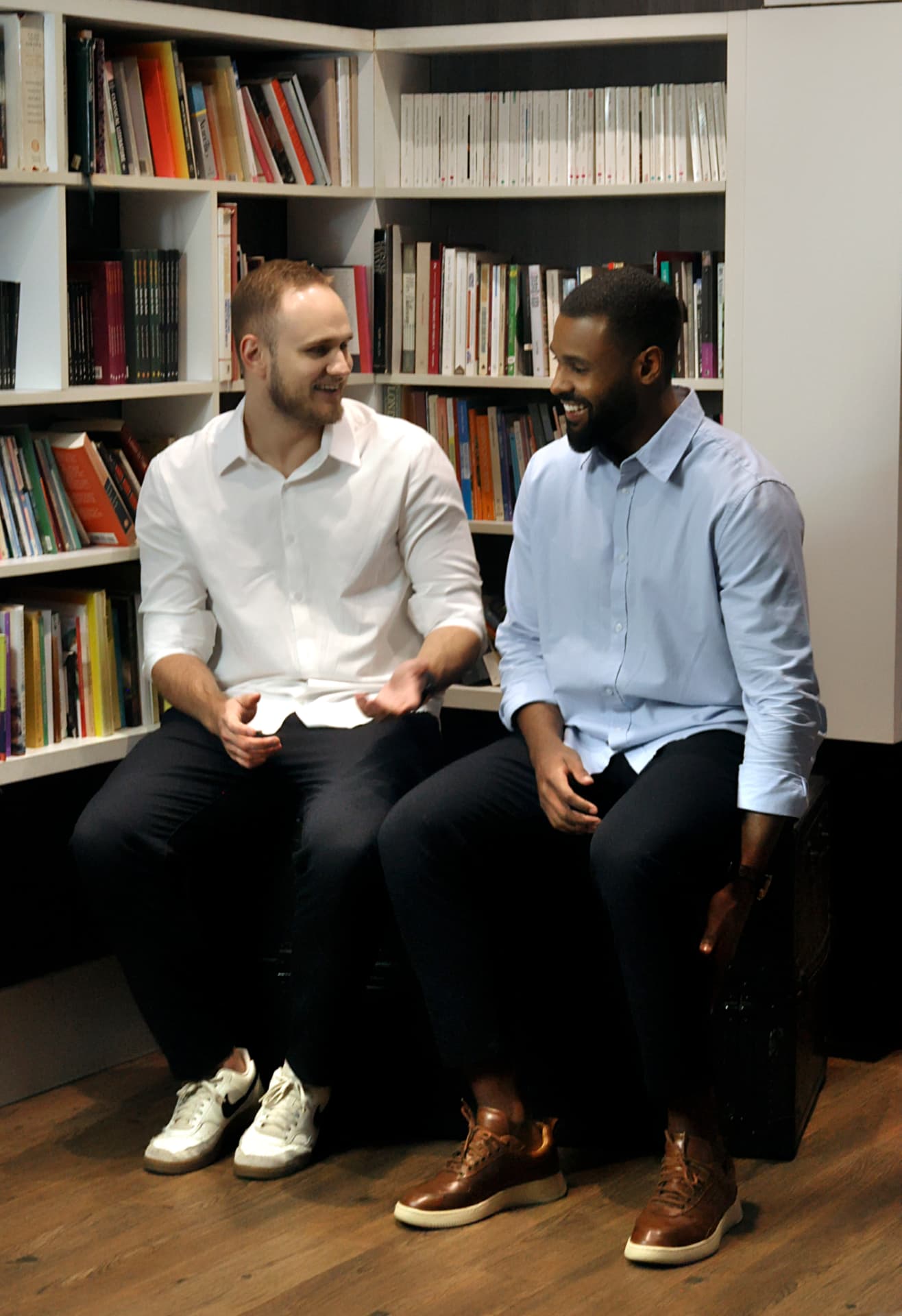 Pedro Beckenkamp e Wesley Souto conversando em frente a uma estante de livros
